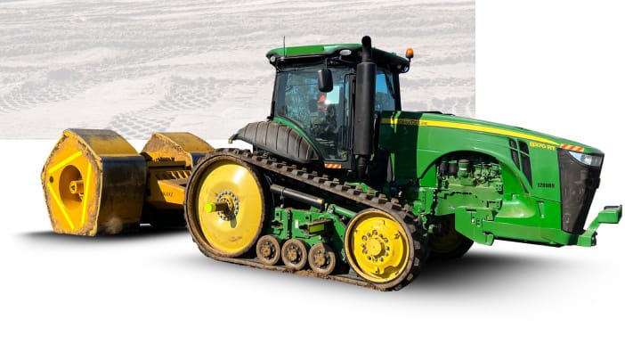 Green John Deere tracked tractor with a large yellow soil compactor/roller attached, on a white background site mockup.